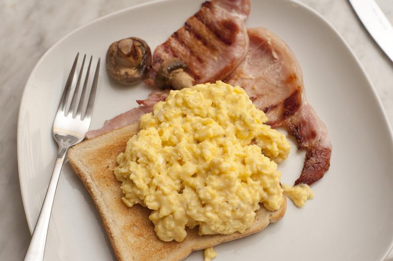 Free Stock Photo: Scrambled eggs and bacon for a nourishing breakfast served on a slice of toast with a mushroom, view from above