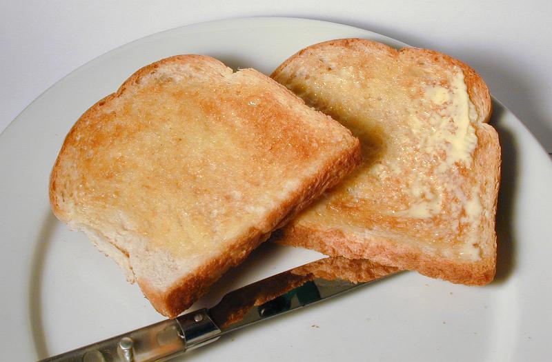 Free Stock Photo: Two slices of hot buttered white toast for breakfast served with a knife on a side plate as an accompaniment to the meal