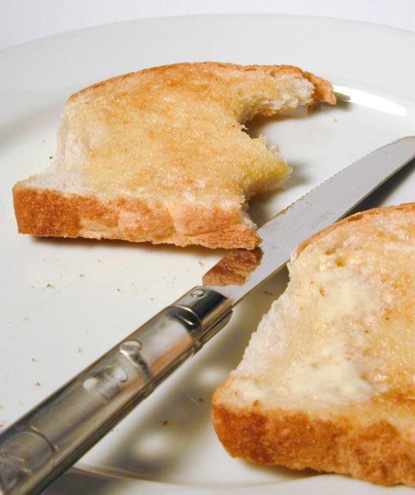 Free Stock Photo: Buttered slices of white toast on a plate with a knife with one slice missing two bites