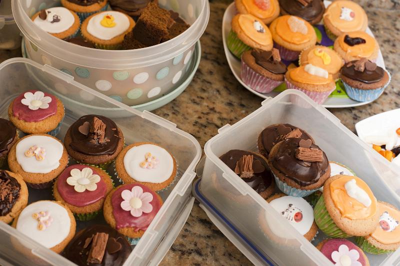 Free Stock Photo: Plastic boxes of freshly baked cupcakes decorated with colorful icing, butterflies and flowers ready for a kids birthday party