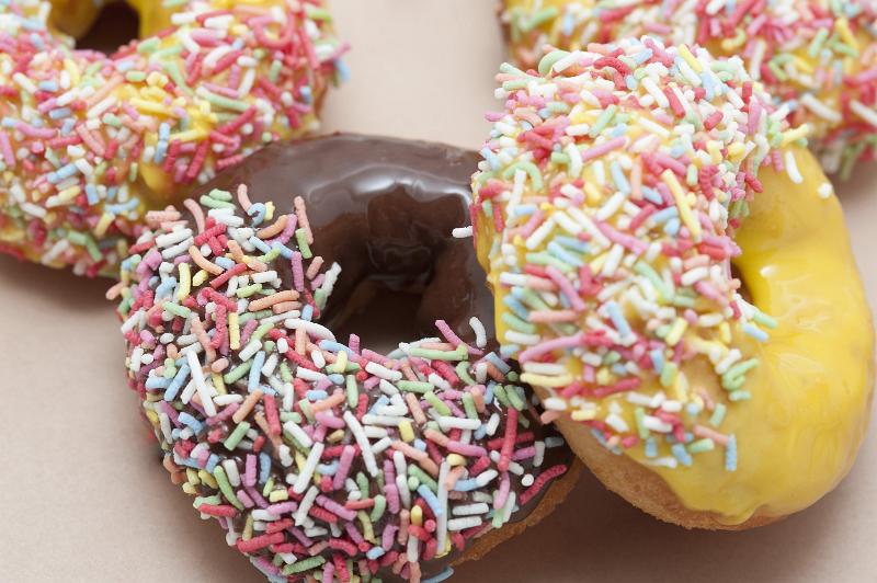 Free Stock Photo: Assorted colorful doughnuts with orange, lemon and chocolate glazing dipped in multicolored sprinkles ready for a tasty snack during a morning coffee break