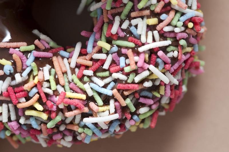 Free Stock Photo: Background texture of a freshly baked decorated chocolate ring doughnut or donut covered in colorful sprinkles