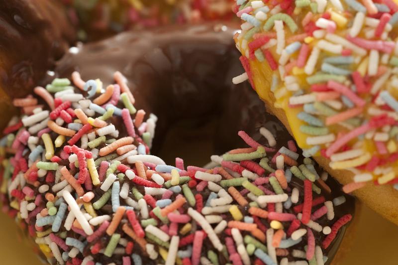 Free Stock Photo: Closeup detail of a decorated ring doughnut glazed with chocolate and orange icing dipped in multicolored sprinkles