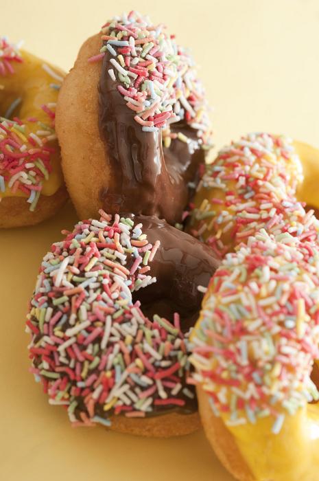 Free Stock Photo: Pile of freshly baked glazed ring doughnuts decorated with colorful sprinkles, closeup side view