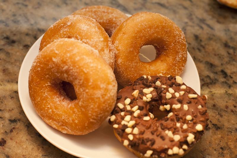 Free Stock Photo: Plate of fresh golden sugared ring donuts with one glazed and decorated doughnut on the side , high angle closeup view