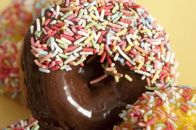 Free Stock Photo: Glazed chocolate and lemon ring doughnuts or donuts covered in colorful candy sprinkles for a kids birthday party or coffee break