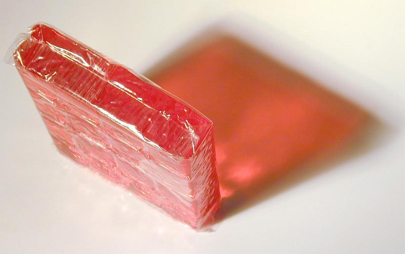 Free Stock Photo: Slab of flavored pink jelly viewed high angle on end casting a colorful shadow on the white surface below