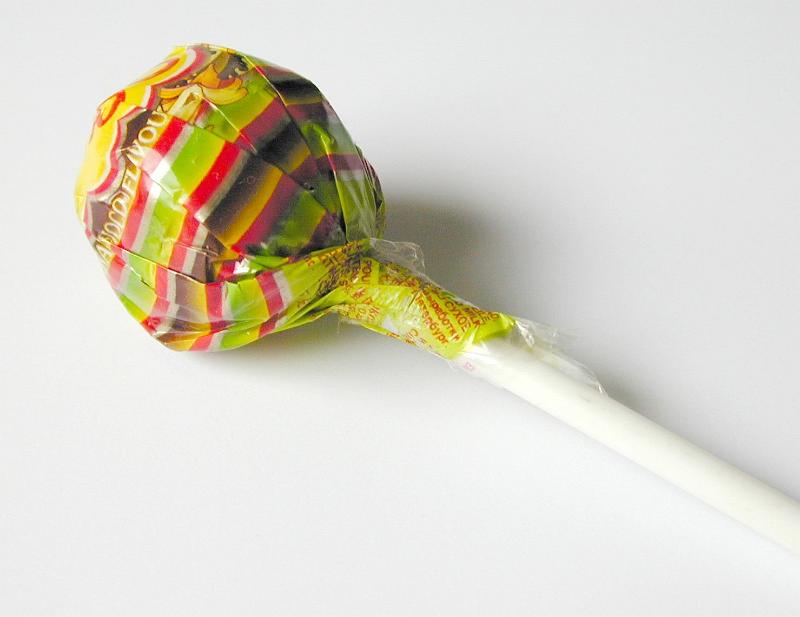 Free Stock Photo: Close-up of a delicious lollipop or lolly wrapped in colorful plastic, with white stick, with copy space on grey