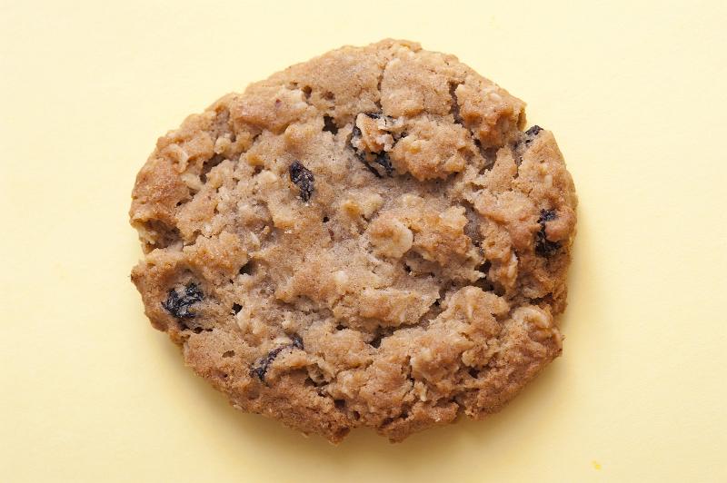 Free Stock Photo: Single round crunchy raisin cookie made with oats on a yellow background, high angle view