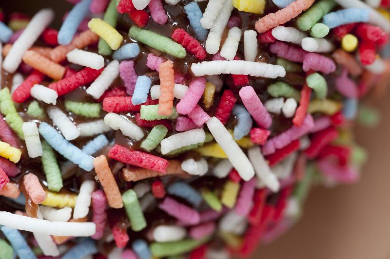 Free Stock Photo: Background texture of multicolored sprinkles on a chocolate glazed doughnut
