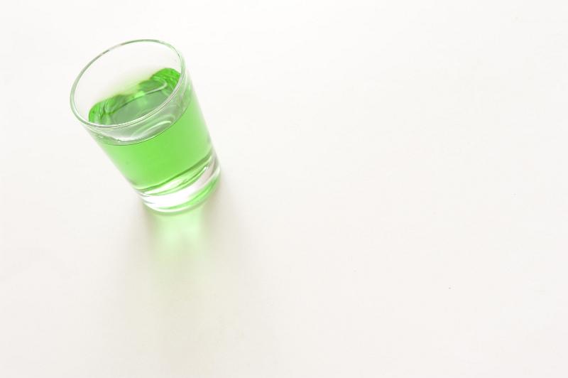 Free Stock Photo: Shot glass of green absinthe, a liquor made from herbs, wormwood and anise with a potent alcohol content, on white with copyspace