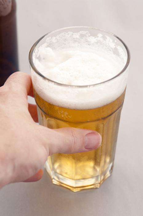 Free Stock Photo: Man reaching for a glass of refreshing cold beer with a frothy head , high angle close up of his hand