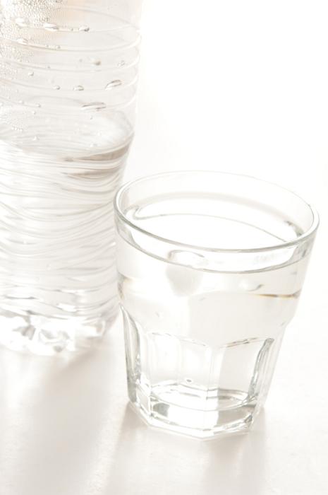 Free Stock Photo: Glass of bottled water with a half full plastic bottle alongside on a white background with copyspace