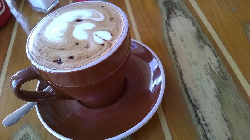 Free Stock Photo: Delicious cup of cappuccino coffee with a decorative pattern in the froth served in a coffee house or cafeteria