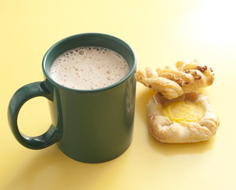 Free Stock Photo: Mug of frothy cappuccino coffee with two cookies for a relaxing coffee break on a yellow background