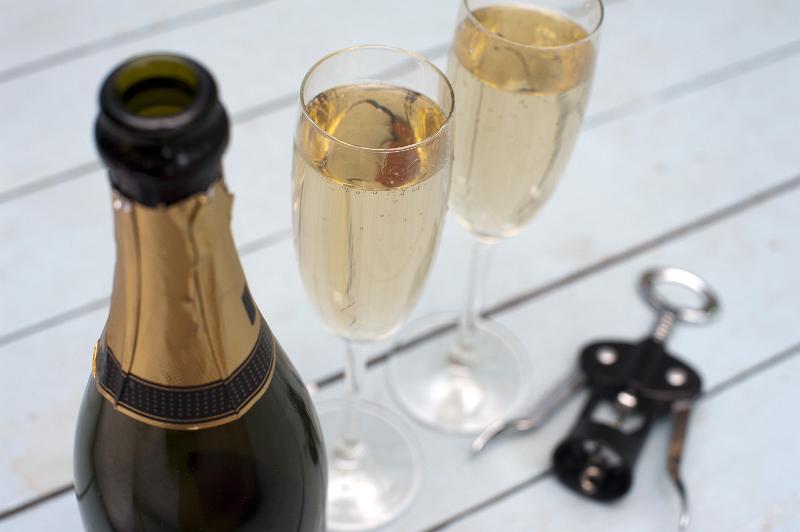 Free Stock Photo: Celebrating with a bottle of champagne with a close up high angle view of the neck of the bottle with a gold label and two full champagne flutes behind for a romantic occasion