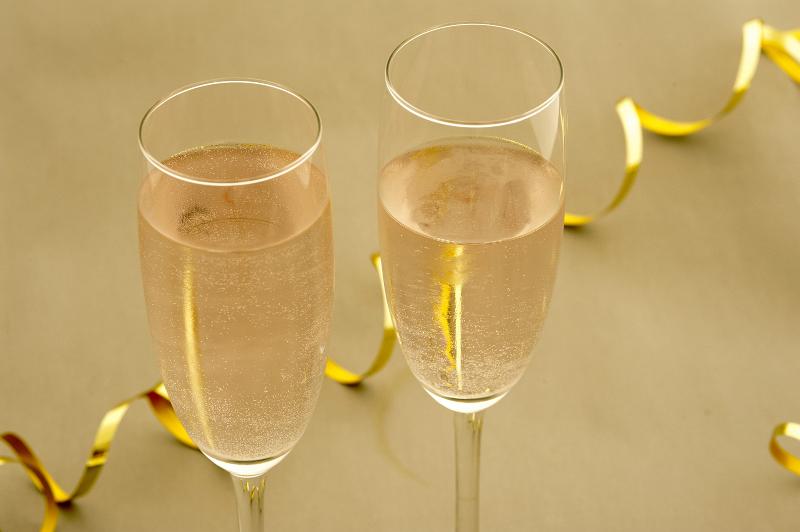 Free Stock Photo: Two flutes of golden bubbly champagne at a romantic party celebration with a diagonal twirled gold streamer behind, close up high angle view