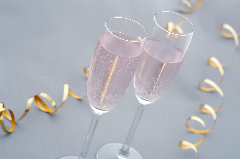 Free Stock Photo: Romantic celebrations with two elegant flutes of pink champagne and twirled golden party streamers, high angle closeup view