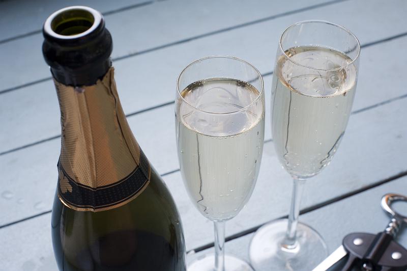 Free Stock Photo: Celebrating with champagne with two flutes full of golden champagne alongside an opened bottle , high angle view with no text on a label visible on the bottle