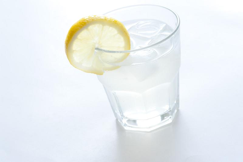 Free Stock Photo: Gin and tonic on ice with lemon in a plain glass tumbler for a refreshing alcoholic beverage on a white background
