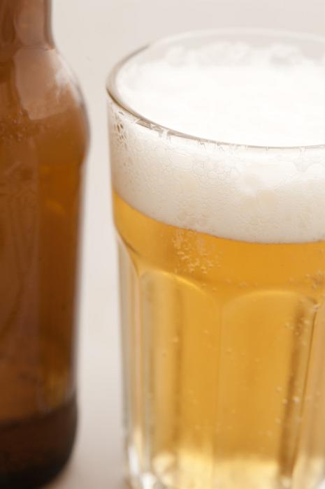 Free Stock Photo: Glass of beer, lager or draft with a good frothy head alongside a brown beer bottle