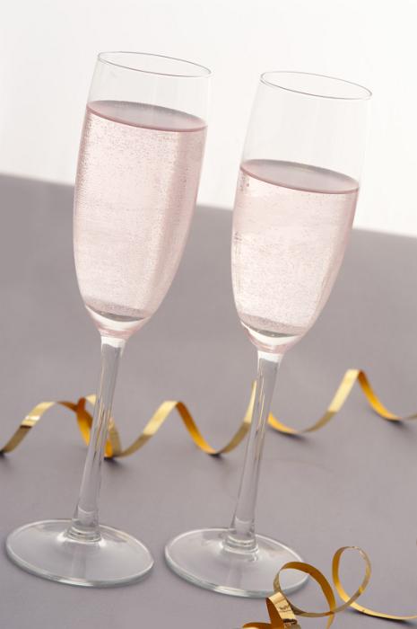 Free Stock Photo: Two elegant flutes of sparkling pink party champagne to celebrate a festive or romantic occasion with a coiled gold decorative streamer