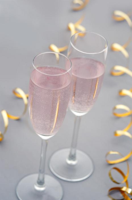 Free Stock Photo: Elegant romantic duo of pink champagne flutes for a party celebration with two twirled gold streamers , high angle on grey