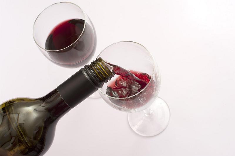 Free Stock Photo: Pouring red wine into wine glasses from a bottle, close up high angle view over a white background with copyspace