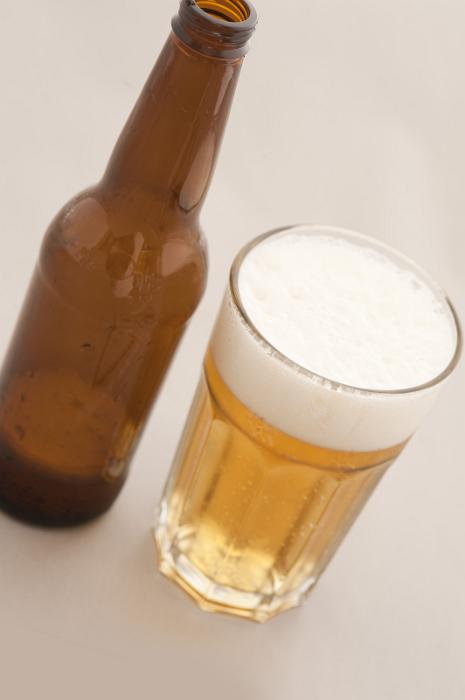 Free Stock Photo: Poured bottled beer in a glass with a good frothy head and unlabeled brown bottle alongside, high angle view