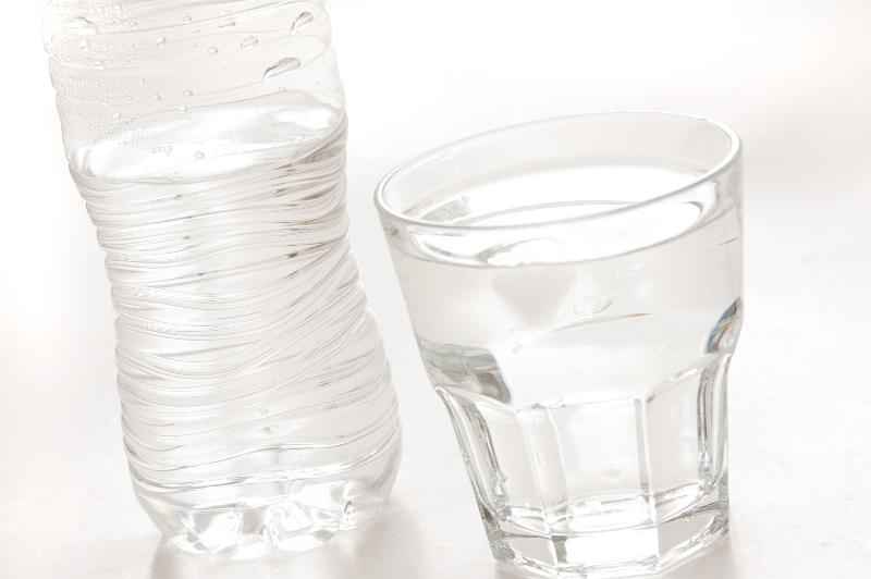Free Stock Photo: Glass of pure bottled water in a glass tumbler with a plastic water bottle behind, over white