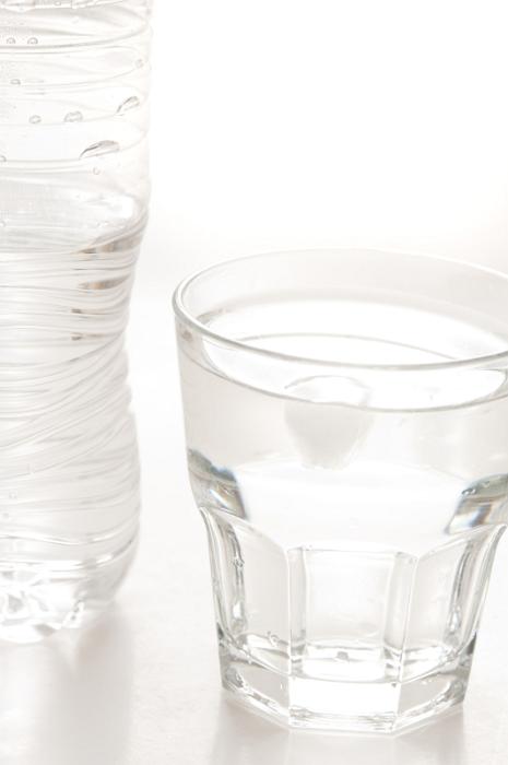 Free Stock Photo: Glass of clean fresh bottled water with the unlabeled plastic water bottle standing alongside on white