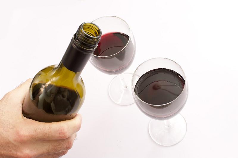 Free Stock Photo: Hand of a man pouring two glasses of red wine from a green unlabeled bottle, high angle view of the glasses