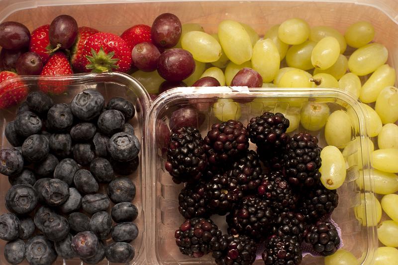 Free Stock Photo: Overhead view of assorted fresh berries and grapes in containers including strawberries, blueberries and blackberries