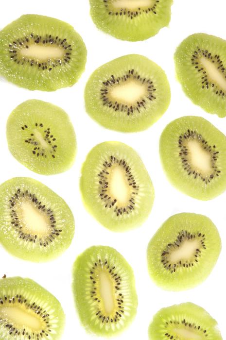 Free Stock Photo: Kiwifruit background pattern and texture with thin slices of peeled fruit arranged randomly on a white background, overhead view