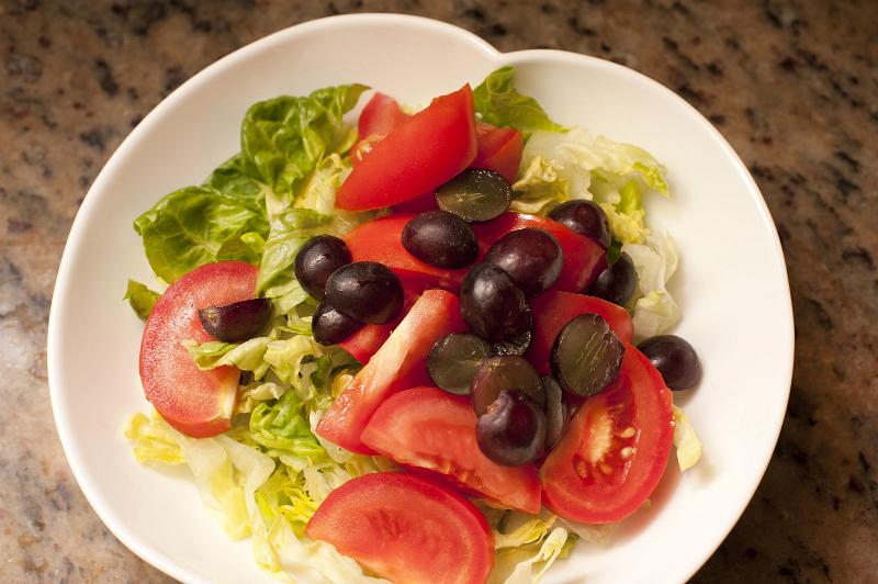 Free Stock Photo: Fresh tomato salad on a plate with leafy green lettuce and fresh grapes for a healthy appetizer or accompaniment to a meal