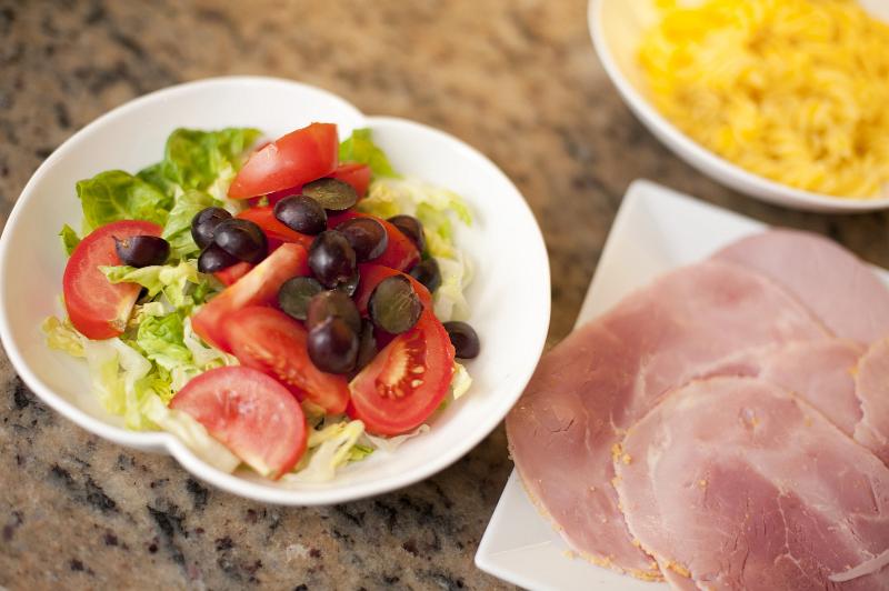 Free Stock Photo: Cold lunch of fresh mixed salad with lettuce, tomato and olives served with a plate of sliced cured ham