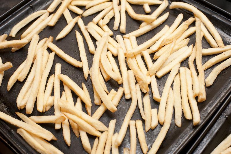 Free Stock Photo: Oven baked potato chips with golden batons spread out on a baking tray while preparing a tasty vegetable accompaniment to a meal