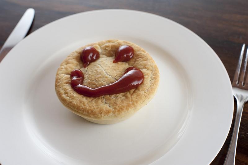 Free Stock Photo: Meat pie with a happy face made of tasty sauce on top of the pastry crust served on a plain white plate