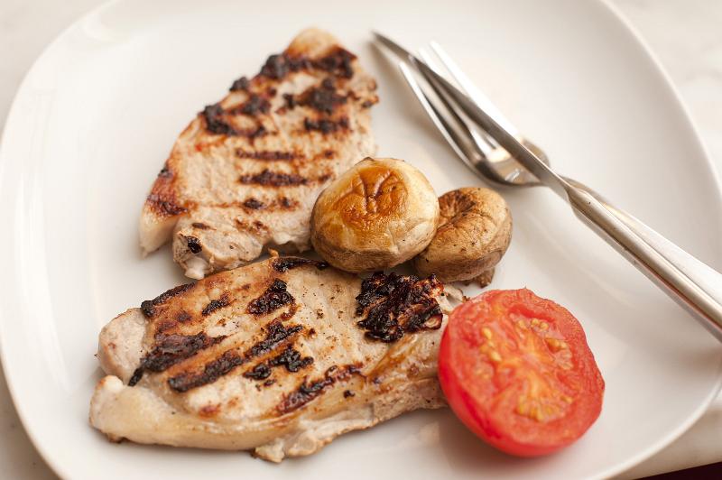 Free Stock Photo: Two delicious lean healthy grilled pork chops served with tomato and mushrooms, high angle view