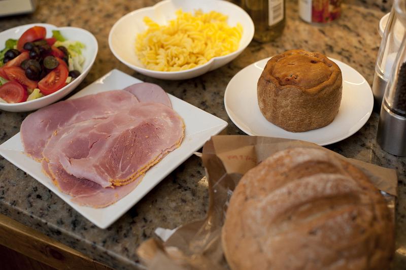 Free Stock Photo: Country meal with ham, salads and a cold pork pie served with a loaf of fresh bread on a rustic table