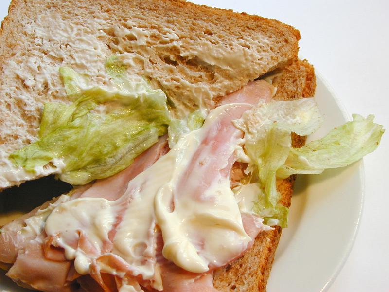 Free Stock Photo: Preparing a sandwich for lunch with thinly sliced ham and lettuce on brown bread, closeup view
