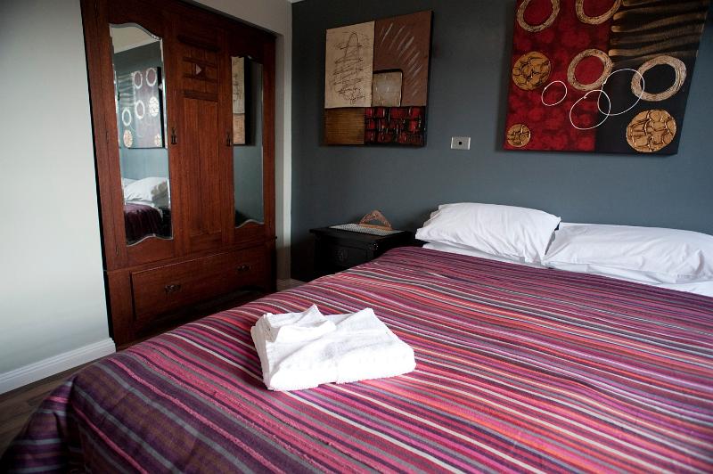 Free Stock Photo: bedroom interior decor with a large double bed, wardrobe with clean towels neatly displayed, and colorful paintings on the wall