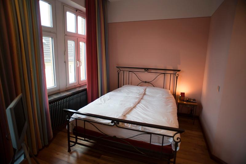 Free Stock Photo: Classic bedroom interior with high windows and a wrought iron double bed illuminated by bedside lamps