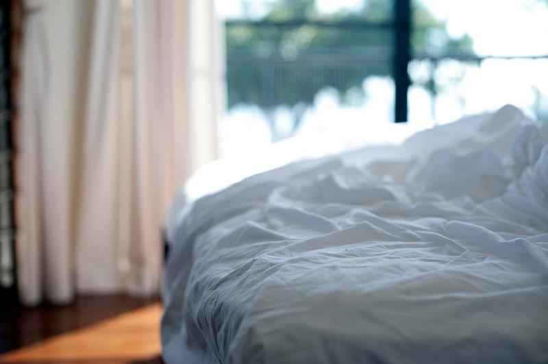 Free Stock Photo: Empty messy unmade bed with white bed linen and crumpled sheets, close up view in front of a bright window