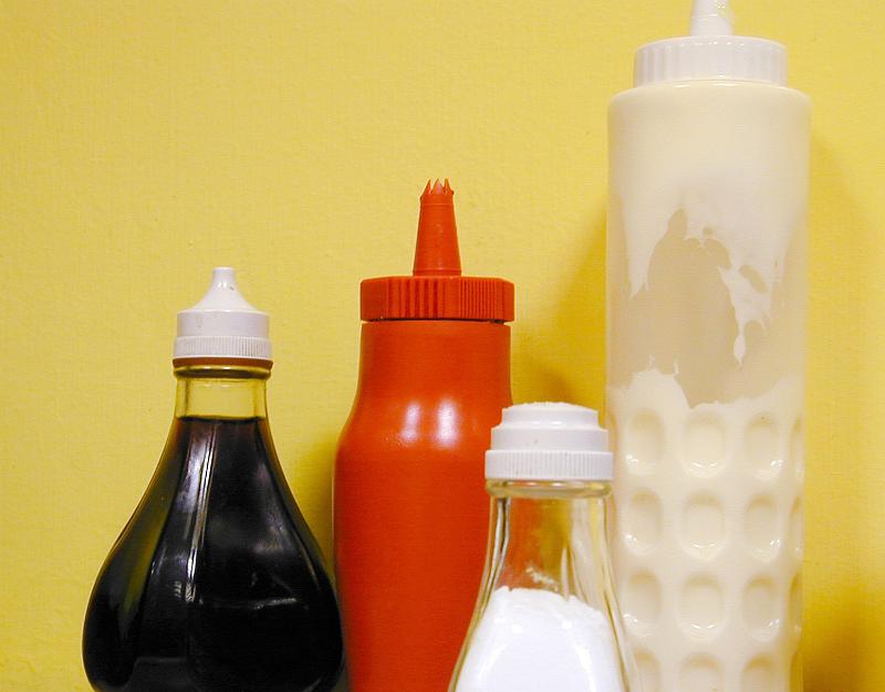 Free Stock Photo: Condiments in a takeaway chip shop in plastic containers including ketchup, mayonnaise , brown vinegar and salt