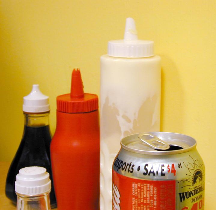 Free Stock Photo: Plastic container with takeaway condiments including vinegar, mayonnaise and salt with a soda can in a chip shop