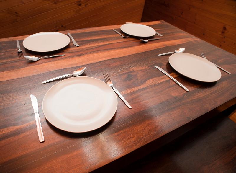 Free Stock Photo: Wooden dinner table set with four place settings with cutlery and empty white ceramic plates