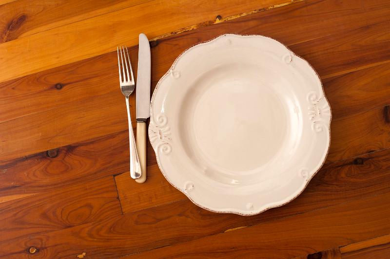 Free Stock Photo: Overhead view of an empty white plate and cutlery on a wooden dining table with decorative wood grain, copyspace