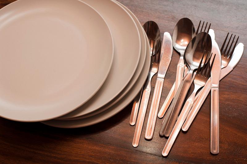 Free Stock Photo: Cutlery and a stack of plates lying ready for use on a wooden table top