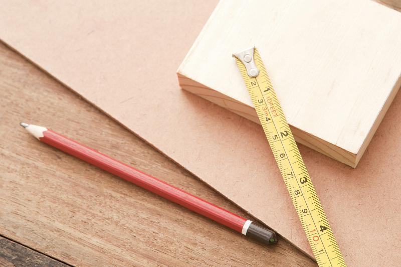 Free Stock Photo: Carpentry background with samples of three different woods, a pencil and builders tape measure marked in centimetres and inches